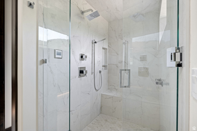 11547 Soaring Hawk Lane Hideout, UT 84036 - Photo 26 of 43 Glass-enclosed shower featuring large format white tiled walls with subtle veining, a built-in tiled bench, a rain showerhead, a handheld shower fixture, and a mosaic tiled floor