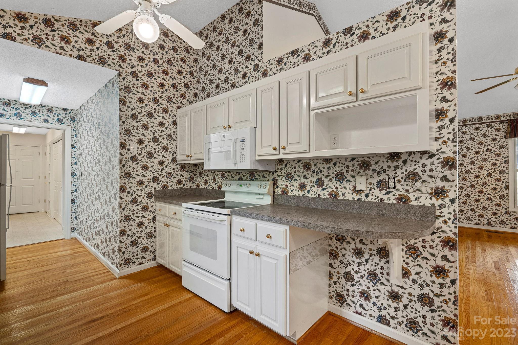 2722 Toddville Road Charlotte, NC 28214 - Photo 11 of 35 a kitchen with white cabinets and wooden floor