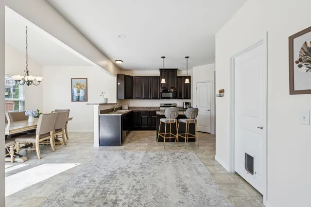 a kitchen with granite countertop a table chairs stove and refrigerator
