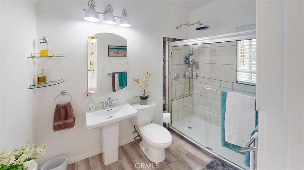 3333 West Keys Lane Anaheim, CA 92804 - Photo 20 of 31 a bathroom with a toilet a sink a light fixture and a glass door shower