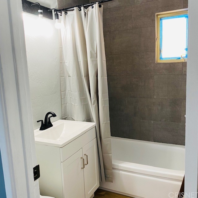 a bathroom with a sink a mirror a bathtub and shower
