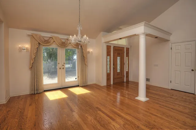 a view of a hallway with wooden floor and a chandelier