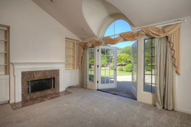 a view of an empty room with a fireplace and a window