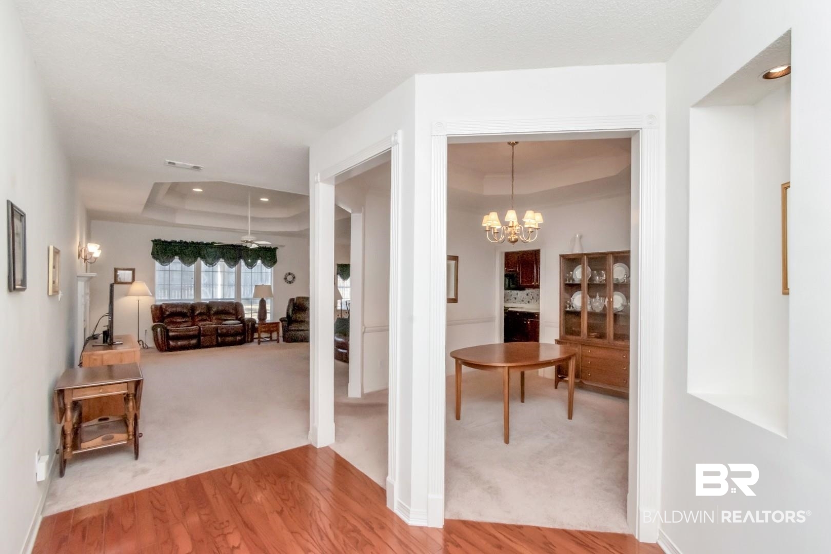 1032 Cross Gates Place Mobile, AL 36609 - Photo 3 of 34 Hall with a tray ceiling, hanging lights, light wood-type flooring, and light carpet