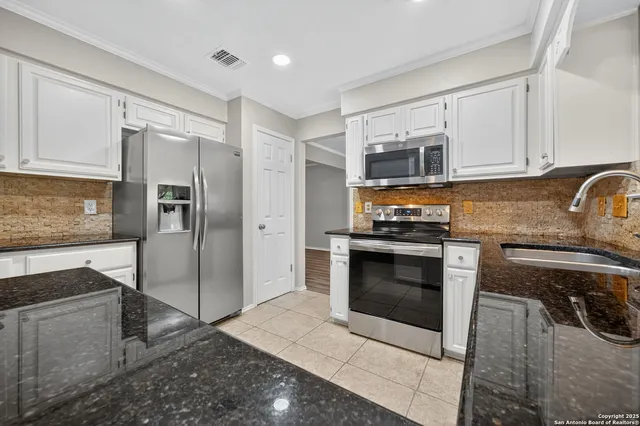 a kitchen with granite countertop a refrigerator stove and microwave