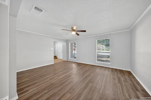 a view of empty room with wooden floor and fan