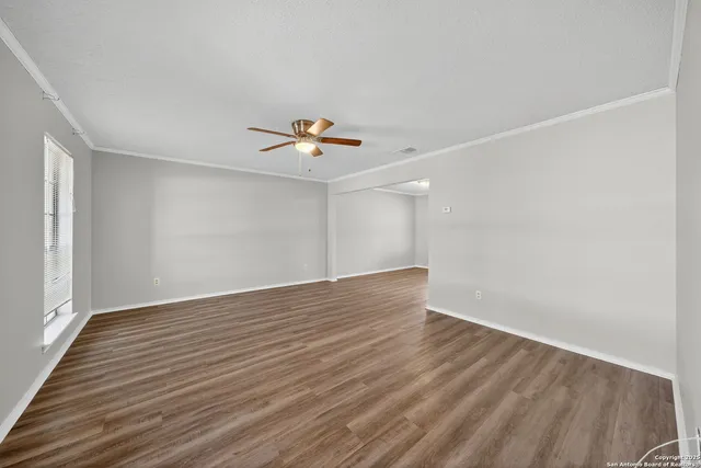a view of an empty room with wooden floor and a window