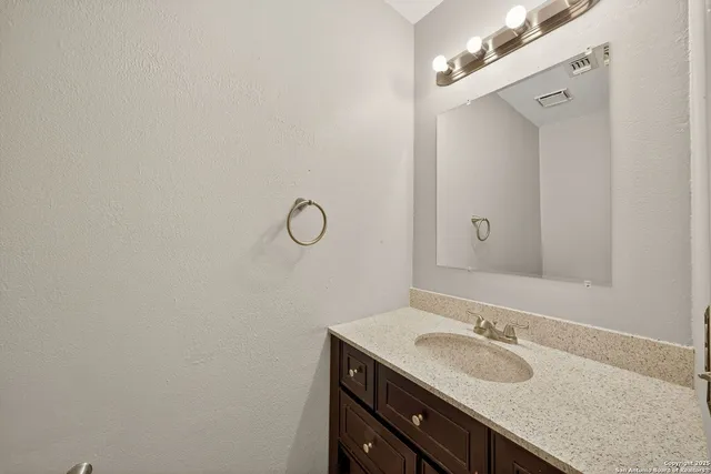 a bathroom with a granite countertop sink and a mirror