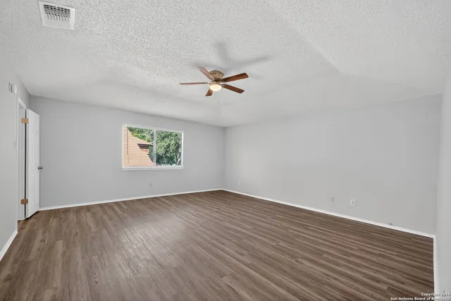 an empty room with wooden floor and a ceiling fan