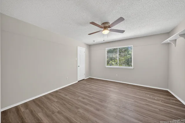 a view of an empty room with a window and wooden floor
