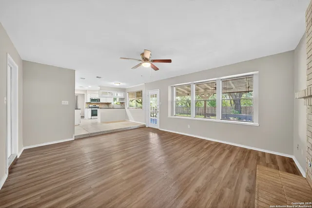 a view of an empty room with a window and wooden floor