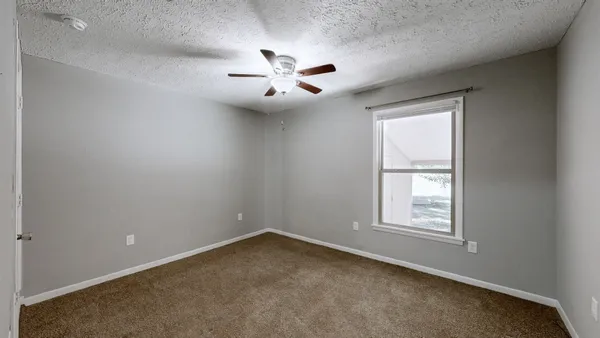 an empty room with windows and fan