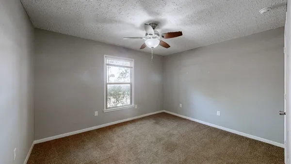 an empty room with a window and ceiling fan