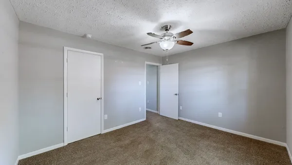 a view of an empty room with a chandelier fan