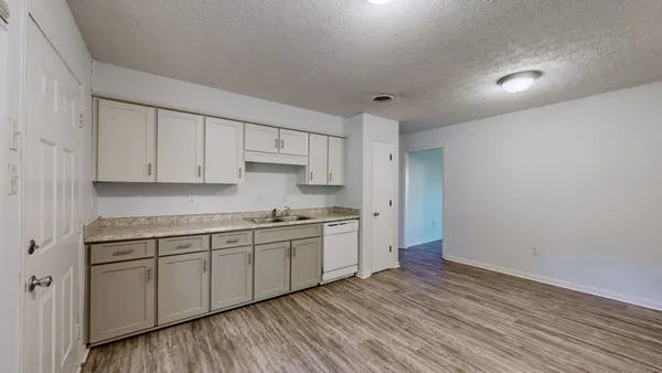 a kitchen with stainless steel appliances granite countertop a sink and cabinets with wooden floor