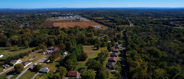 an aerial view of residential houses with outdoor space and trees