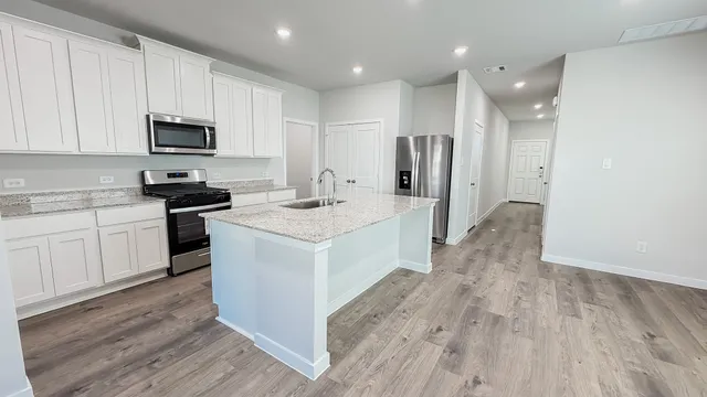 a kitchen with a sink a microwave a refrigerator and cabinets