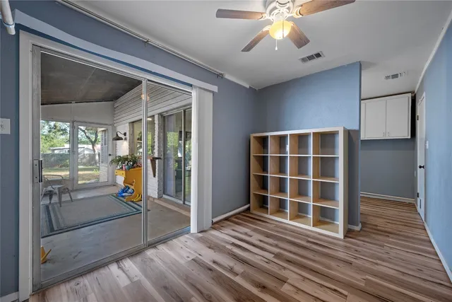 a view of empty room with wooden floor and fan