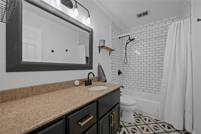 a bathroom with a granite countertop sink toilet and shower