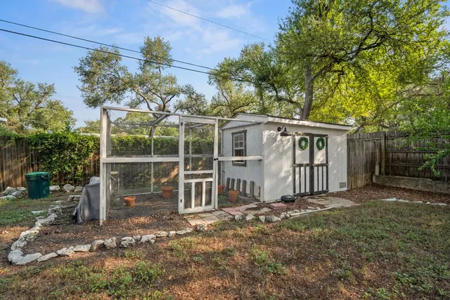 a white house that has a small yard and large trees