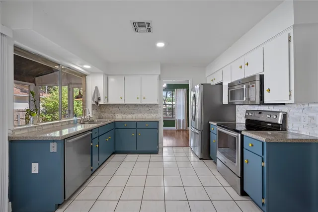 a large kitchen with stainless steel appliances granite countertop a stove top oven a sink dishwasher and a refrigerator