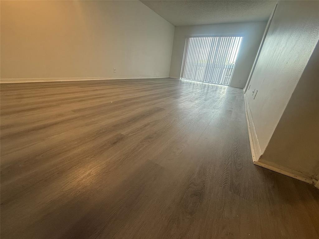 7960 North Colony Circle Tamarac, FL 33321 - Photo 5 of 11 an empty room with wooden floor and windows with curtains