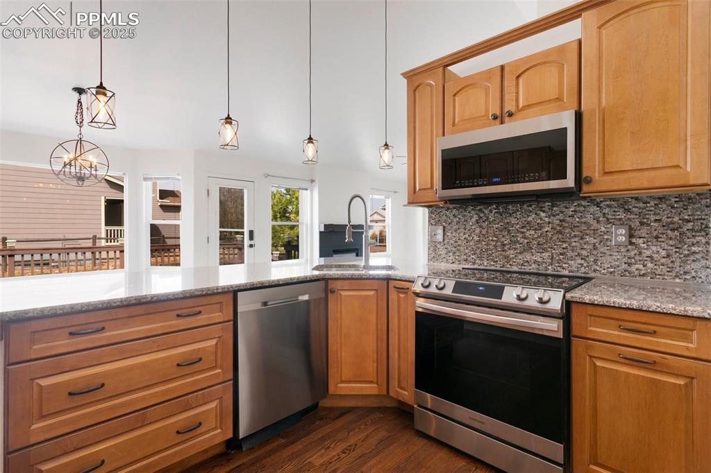 8946 Oakmont Road Peyton, CO 80831 - Photo 12 of 35 a kitchen with stainless steel appliances a stove microwave and cabinets