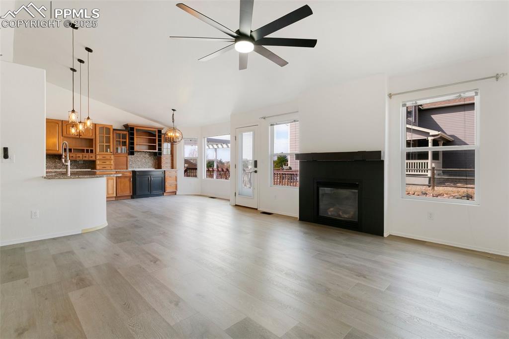 8946 Oakmont Road Peyton, CO 80831 - Photo 4 of 35 an empty room with wooden floor a ceiling fan a fireplace and windows