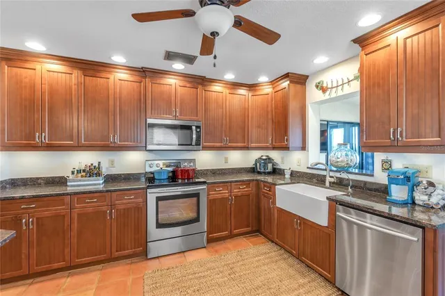 a kitchen with stainless steel appliances granite countertop wooden cabinets a sink dishwasher a stove and a refrigerator with wooden cabinets