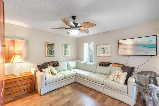 a living room with furniture a ceiling fan a lamp and a window