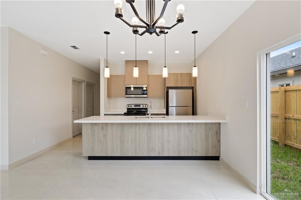 1806 West Violet Drive, Unit 1 Pharr, TX 78577 - Photo 5 of 15 a large white kitchen with a large counter top space a sink stainless steel appliances and cabinets