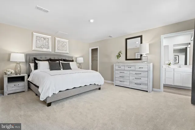 a spacious bedroom with a bed a lamp and a large mirror