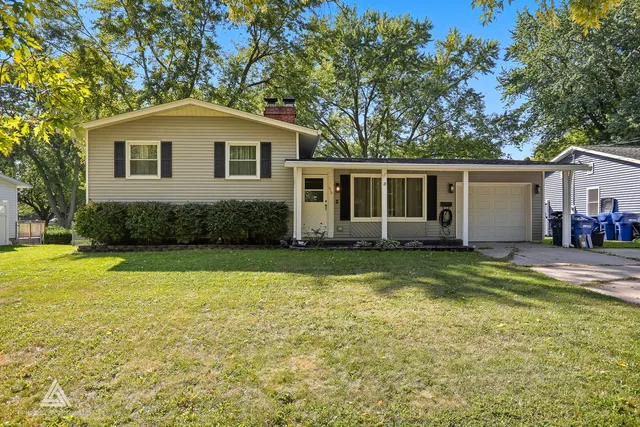 a front view of house with yard and trees in the background
