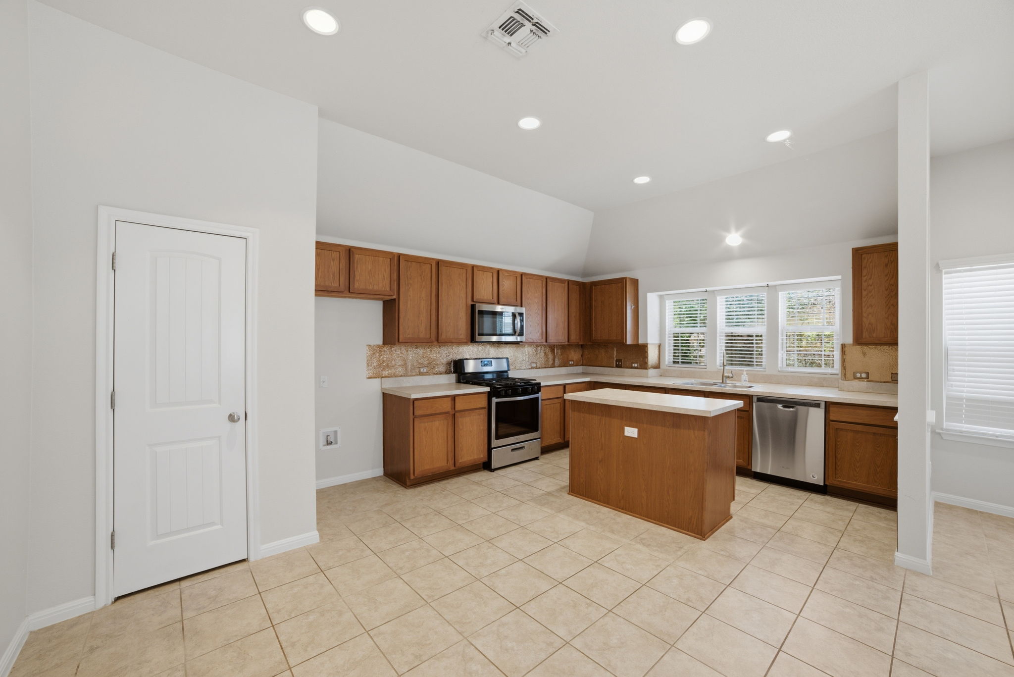 514 Nautical Loop Kyle, TX 78640 - Photo 11 of 24 A well-lit kitchen features modern stainless steel appliances and abundant cabinetry, centered by a practical island.