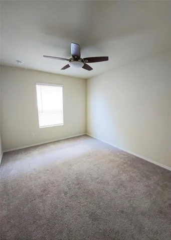 an empty room with a window and a ceiling fan