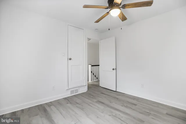 an empty room with wooden floor ceiling fan and window