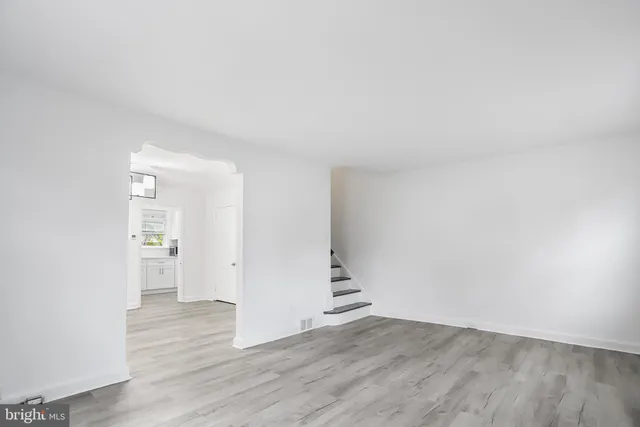 an empty room with wooden floor & windows