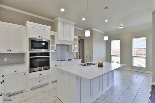 a large kitchen with stainless steel appliances a stove a sink and a refrigerator