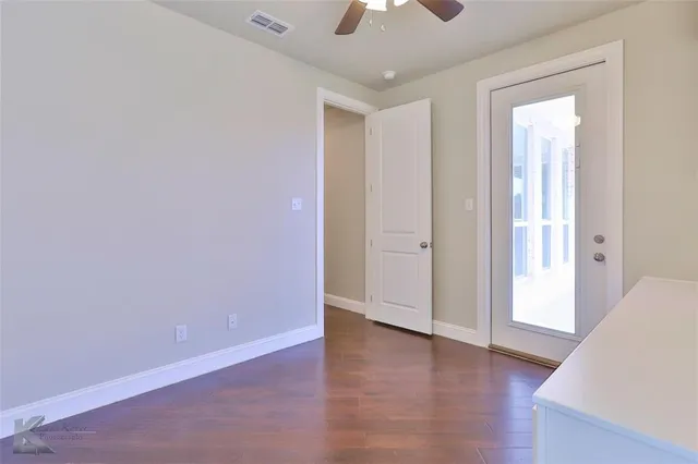an empty room with wooden floor and a ceiling fan