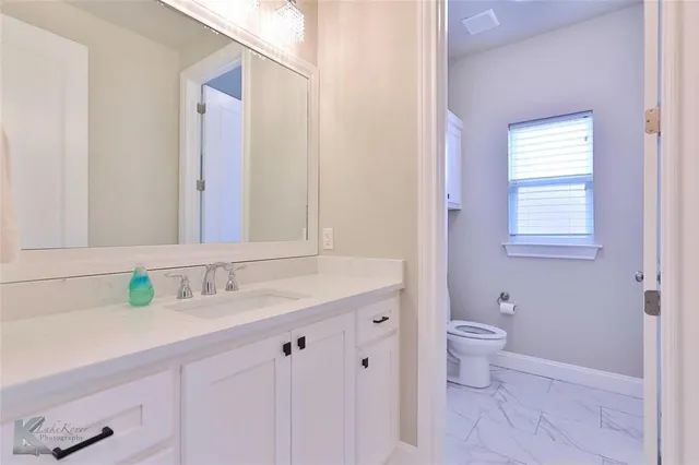 a bathroom with a granite countertop sink a toilet and a mirror