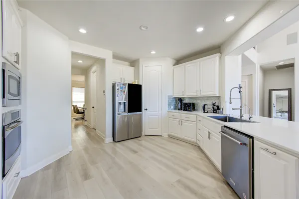 a large kitchen with stainless steel appliances refrigerator a stove top oven with wooden floors