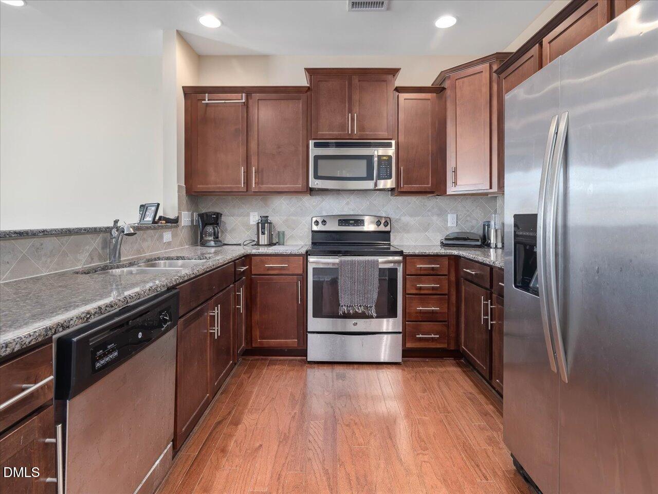 409 Provincial Street Raleigh, NC 27603 - Photo 10 of 44 a kitchen with stainless steel appliances granite countertop a stove top oven a sink and dishwasher