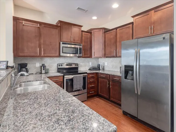 a kitchen with stainless steel appliances granite countertop a stove top oven a sink and dishwasher