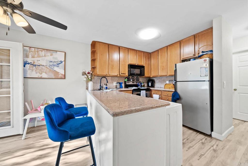 a kitchen with stainless steel appliances granite countertop a refrigerator a sink a stove a dining table and chairs with wooden floor