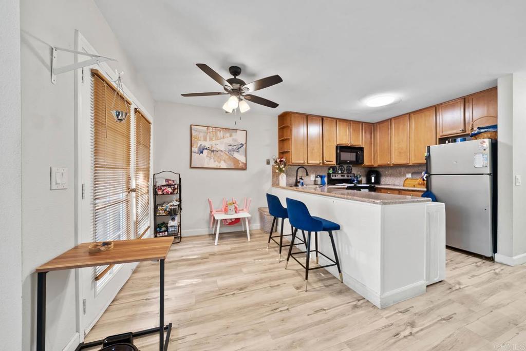 1280 West Main Street, Unit 42 El Cajon, CA 92020 - Photo 13 of 43 a kitchen with stainless steel appliances granite countertop a refrigerator a stove a sink a dining table and chairs with wooden floor