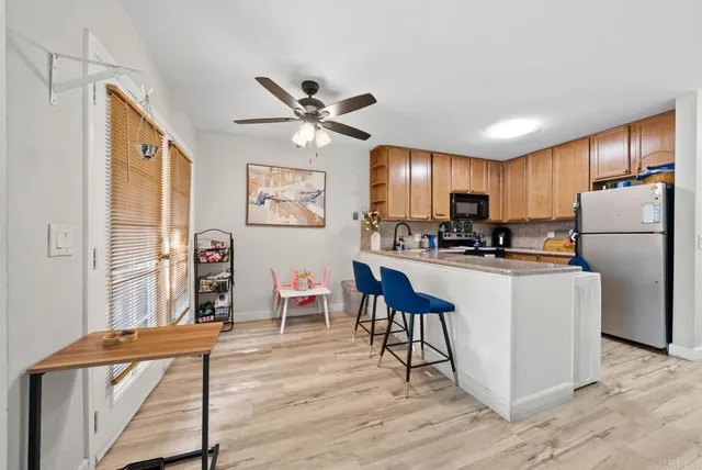 a kitchen with stainless steel appliances granite countertop a refrigerator a stove a sink dishwasher and a dining table with wooden floor