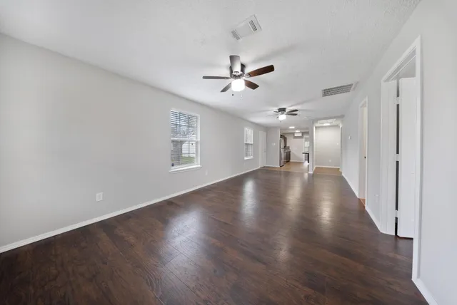 a view of empty room with wooden floor and ceiling fan