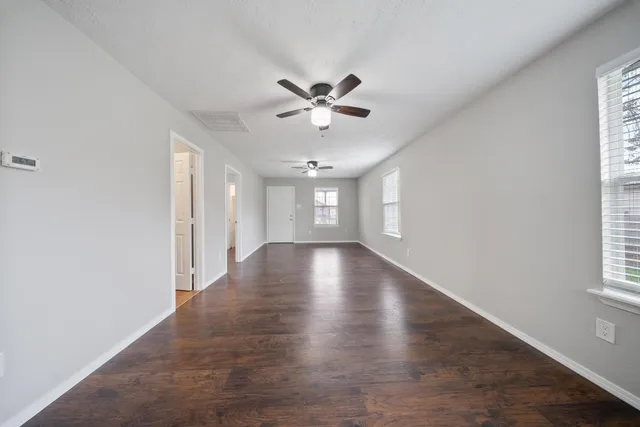 an empty room with wooden floor and windows