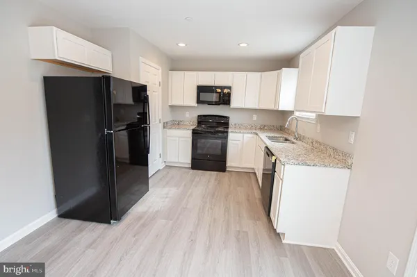 a view of a kitchen with a fridge and wooden floor