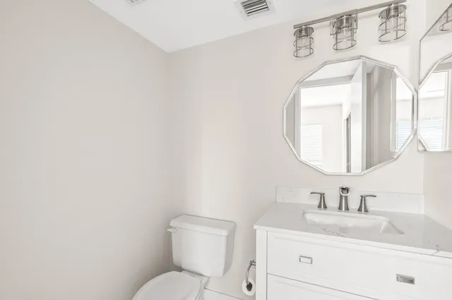 a bathroom with a toilet sink vanity and mirror